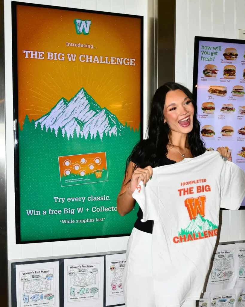 Customer holding a big w challenge punch card and warrens big w burger at a northern utah restaurant location