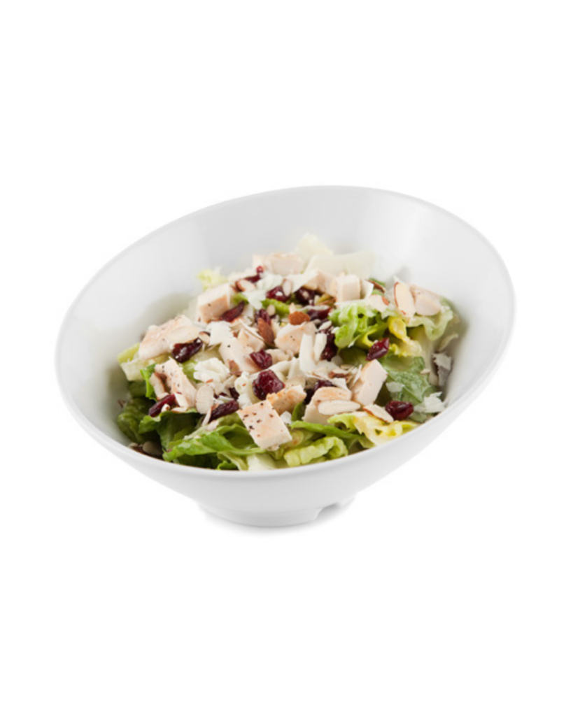 Chicken salad with greens diced chicken almonds and dried cranberries in a white bowl