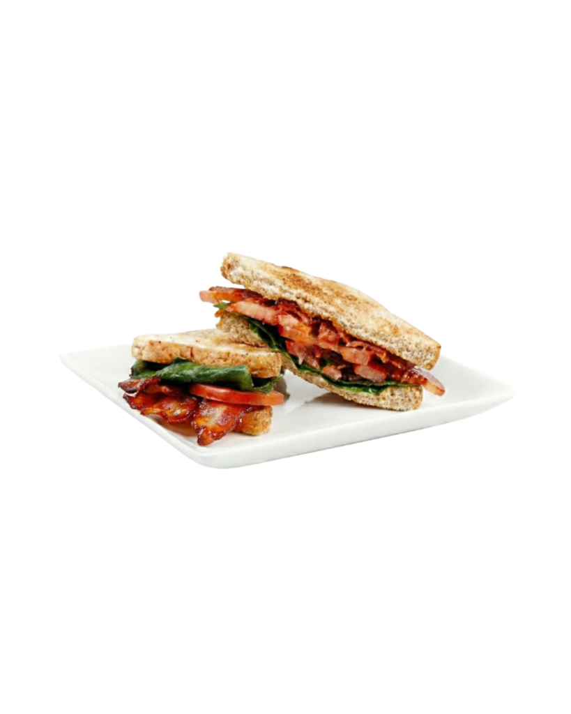 Blt style sandwich with crispy bacon tomato and greens on toasted bread halved on a white plate