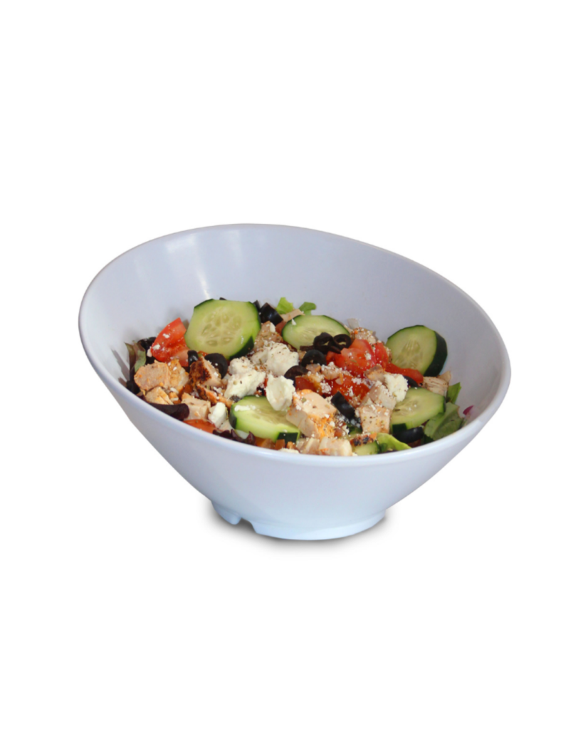 White ceramic bowl of greek salad with cucumber tomato olives feta and chicken pieces