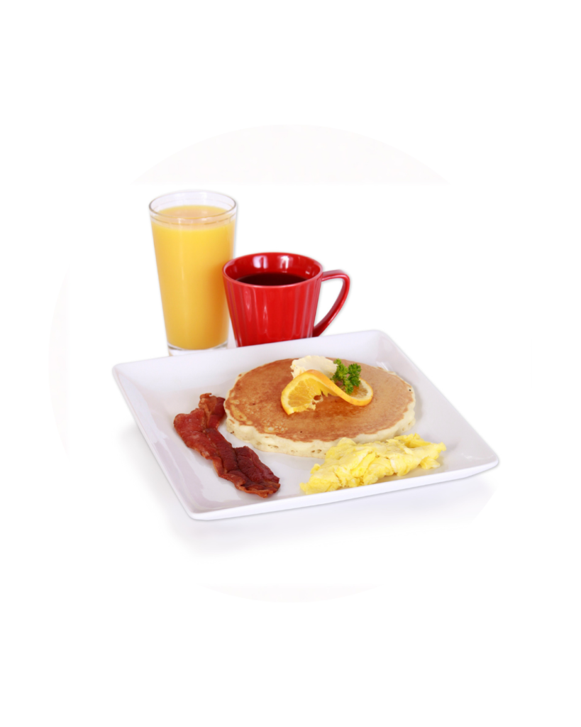 Breakfast plate with pancake scrambled eggs bacon orange slice on top plus glass of orange juice and red coffee mug on the side