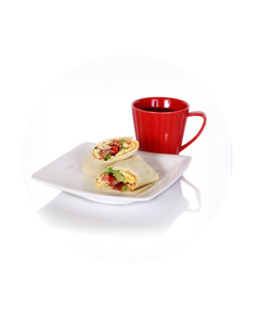 Two veggie filled wrap halves on a white plate beside a red mug