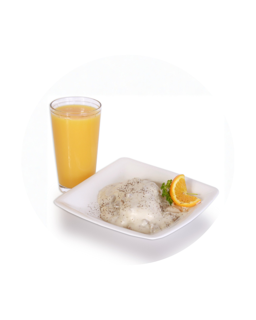 Plate with creamy chicken in white sauce pepper sprinkled on top garnished with parsley and an orange slice beside a glass of orange juice