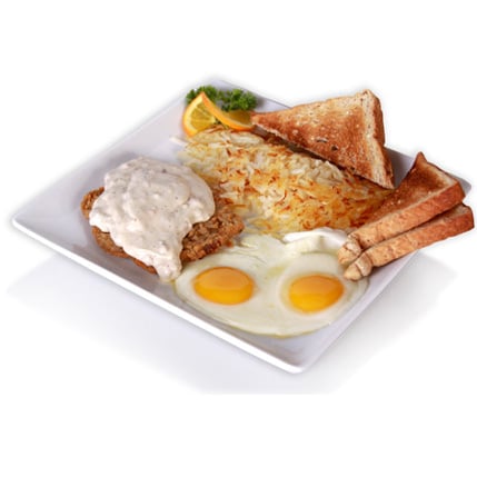 Plate with two sunny side eggs hash browns country fried steak with gravy toasted bread triangles orange slice garnish and two breadsticks