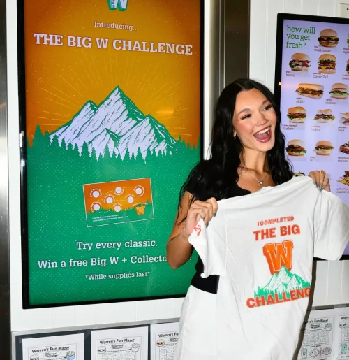 Customer holding a Big W Challenge punch card and Warrens Big W Burger at a Northern Utah restaurant location.
